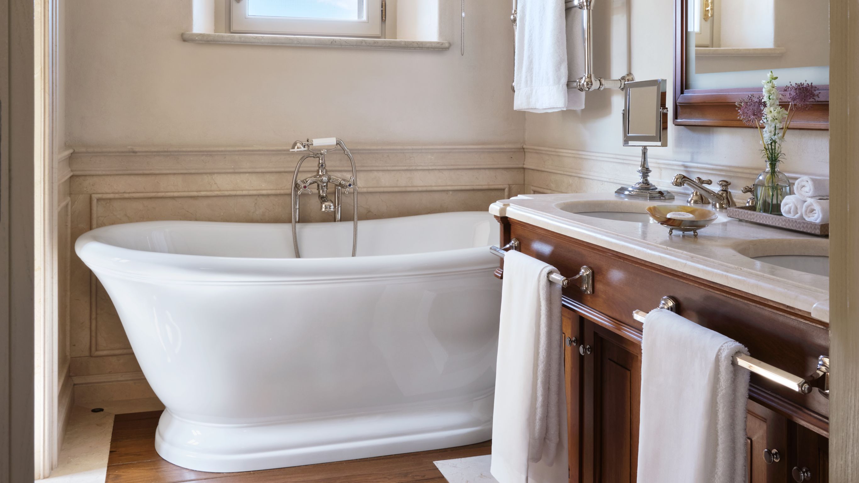 Bathroom with a freestanding white bathtub,  sink, mirror, and towels
